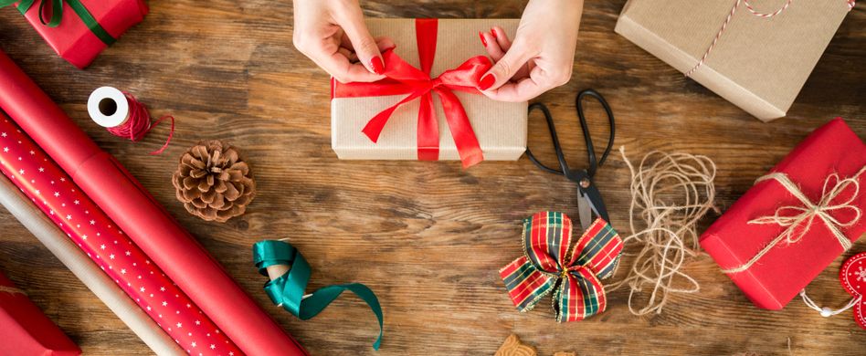 frau bindet schleife um weihnachtsgeschenk