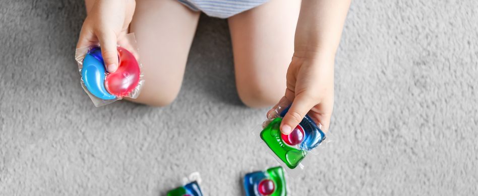 Kind spielt mit Waschkapseln, Waschgelkapseln. Halten Sie Haushaltschemikalien von Kindern fern