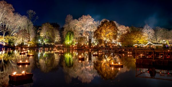 see mit vielen lichtern bei nacht und beleuchteten bäumen