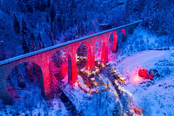 weihnachtsmarkt im wald unter einer brücke mit schneebedeckter umgebung