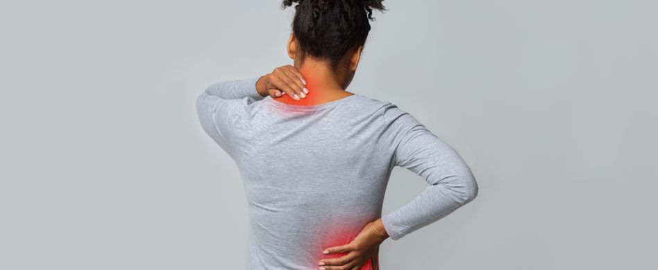 frau steht vor grauem hintergrund und hält sich den rücken an rot markierten stellen vor schmerzen