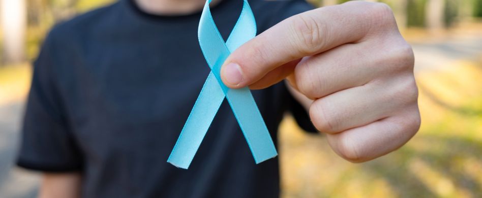 mann im wald hält blaue schleife als zeichen für krebs