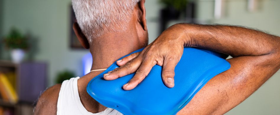 mann hält sich blaue wärmflasche auf die schulter und den rücken