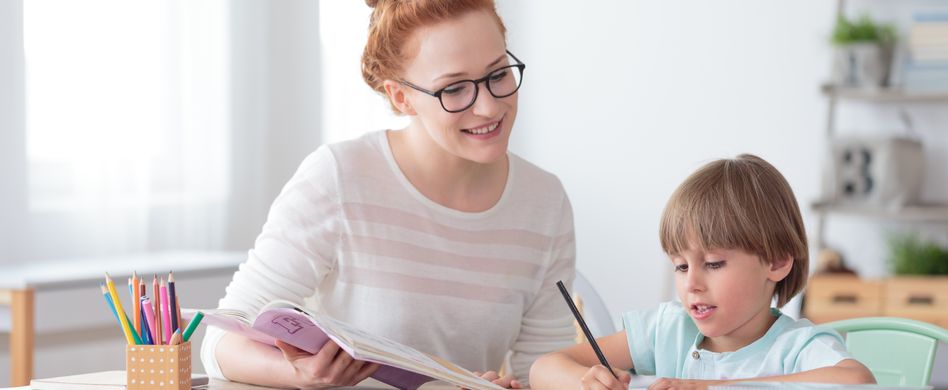 frau sitzt mit kind an schreibtisch und lernt