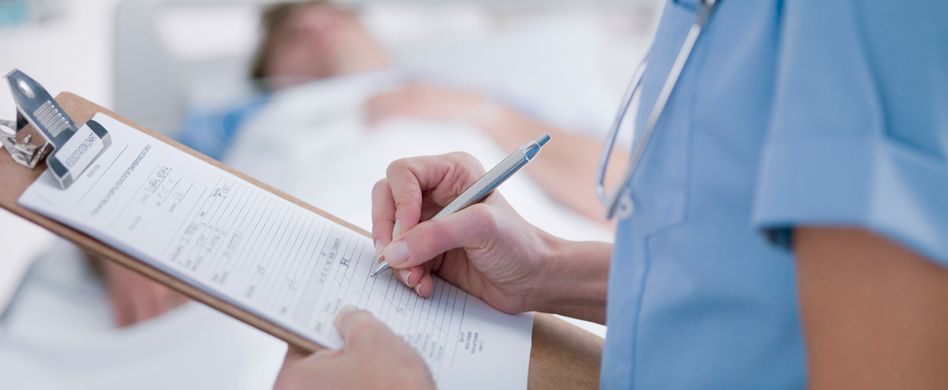 ärztin steht mit klemmbrett vor bett in dem kranke person liegt