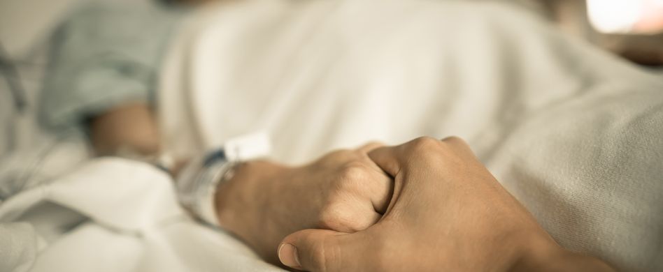 pfleger oder pflegerin arzt ärztin hält hand von im bett liegenden mann