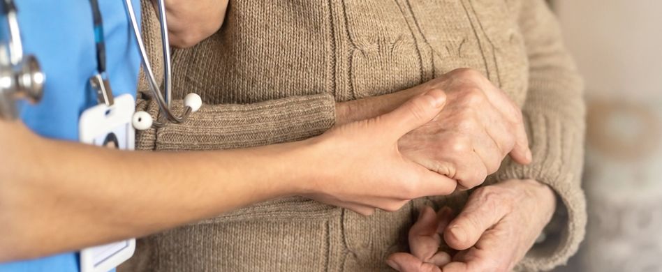ärztin mit stethoskop hält hand von patientin in braunem pullover