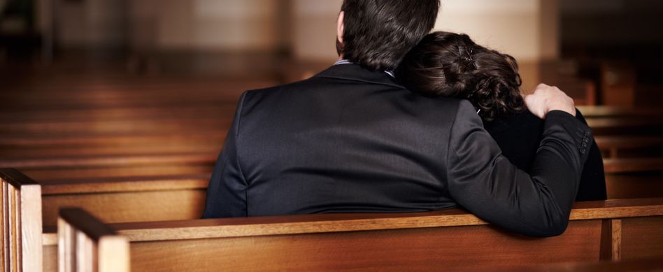 frau und mann sitzen im trauersaal und trösten sich