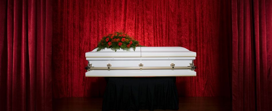 weißer sarg mit roten blumen obendrauf vor roter wand