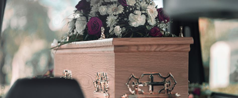 blumen auf einem sarg im leichenwagen