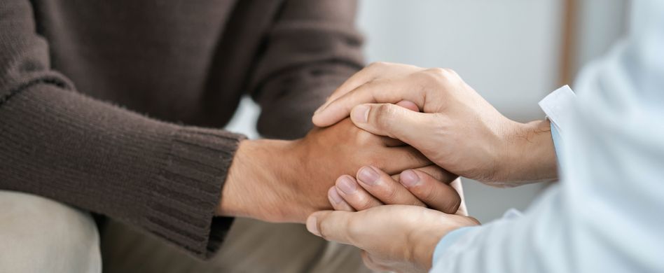 zwei menschen halten sich die hände zum trösten