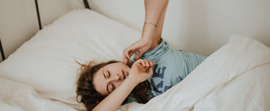 frau liegt im bett mit armen nach oben