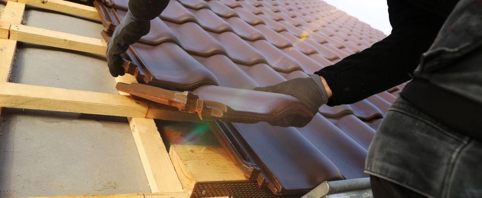 dachdecker setzt dachziegel auf ein dach