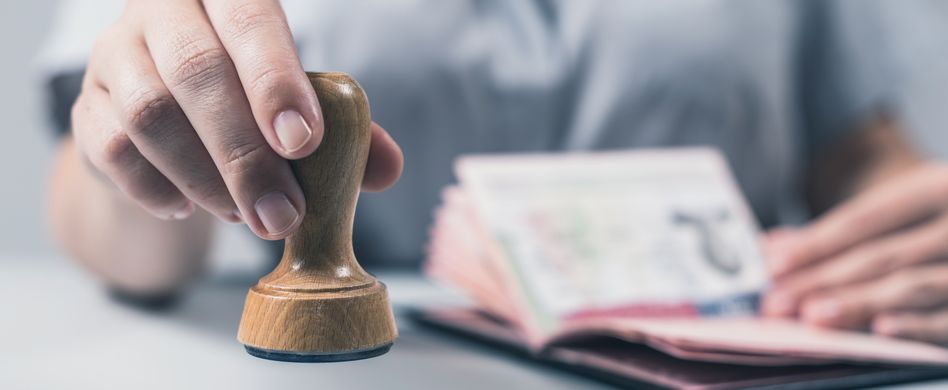 mann drückt stempel auf reisepass