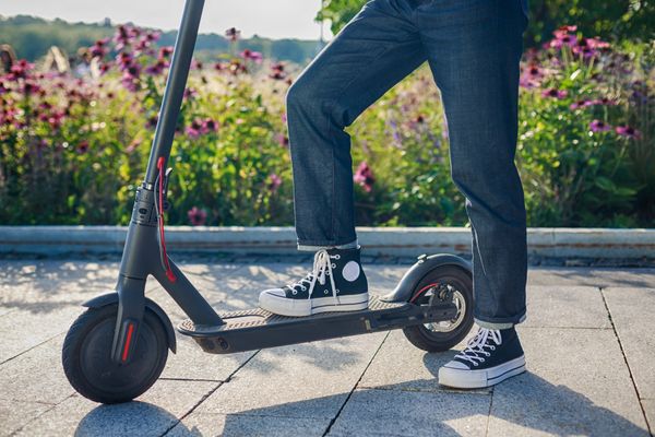 person mit blauer jeans und schwarz-weißen schuhen auf e-roller im im park