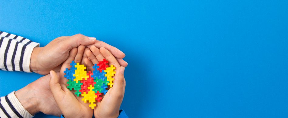 zwei hände halten herz aus puzzleteilen auf blauem hintergrund