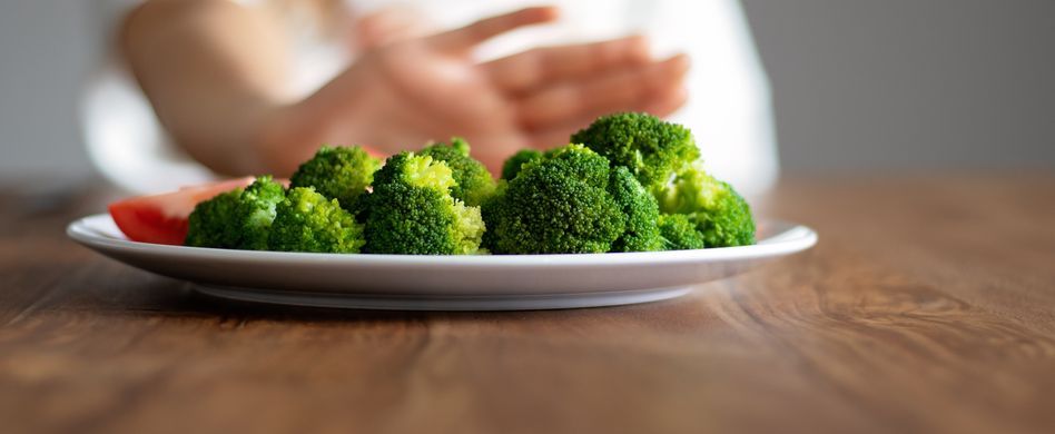 teenager schiebt teller mit brokkoli von sich weg