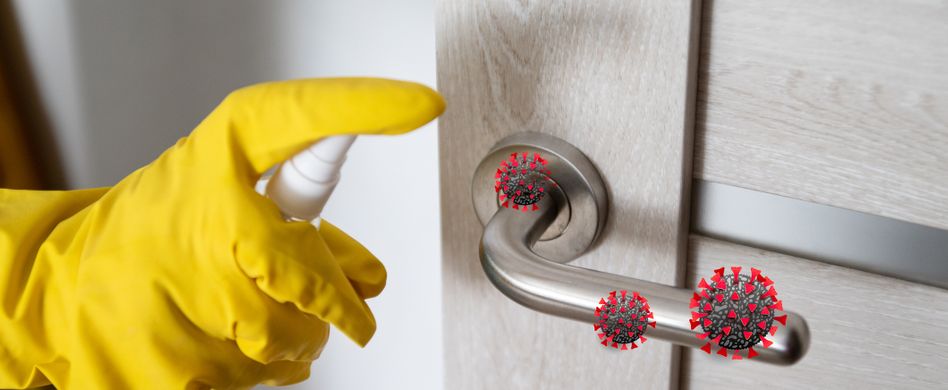 person desinfiziert türklinke mit handschuhen vor viren