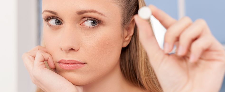 Frau hält Tablette zwischen den Fingern