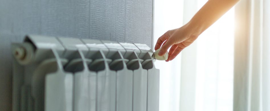 frau dreht an regler der heizung