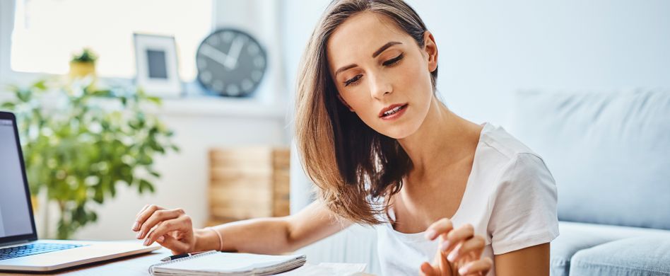 frau rechnet kosten aus mit taschenrechner und laptop