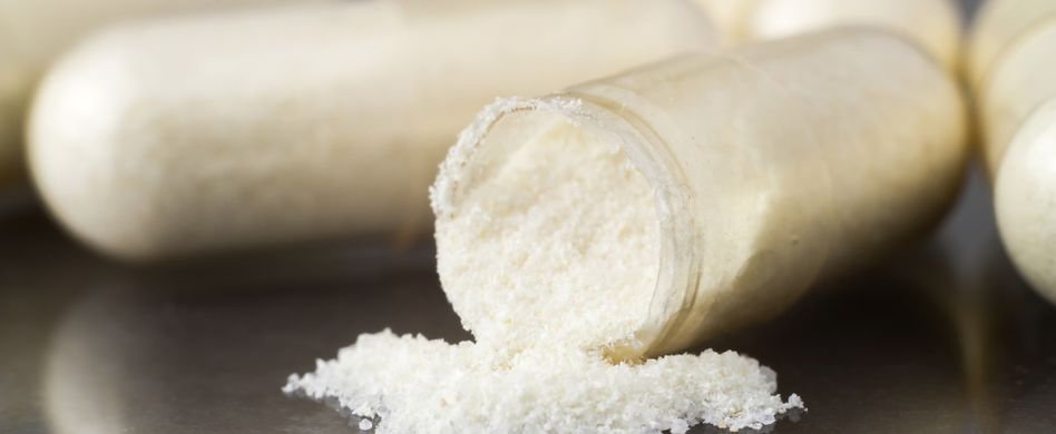 offene glucosamin kapseln auf dunklem hintergrund