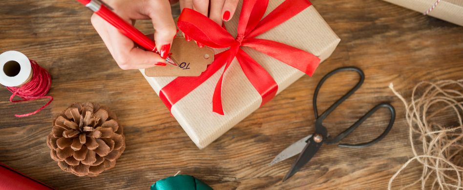 frau hält geschenkverpackung mit rotem geschenkband in den händen