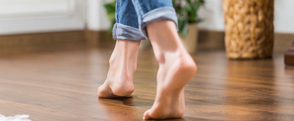 frau läuft barfuß auf dunkelbraunem laminatboden