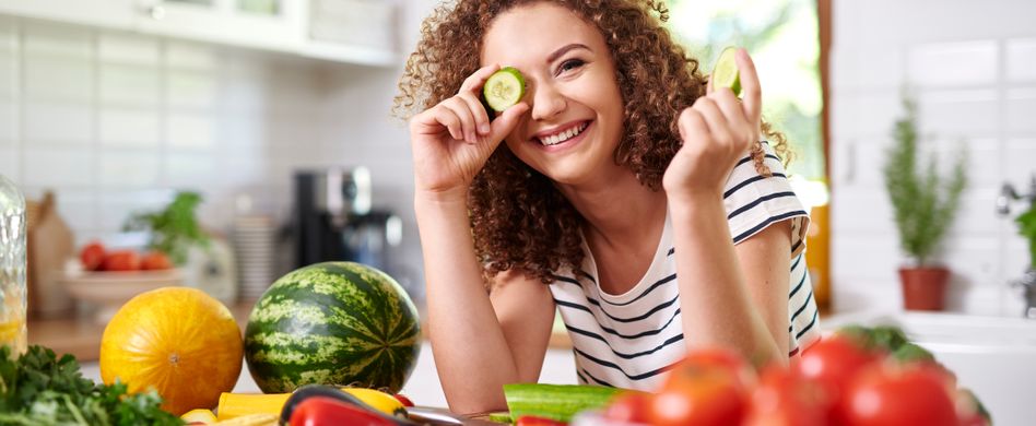 Frau mit Genüse und Gurke in Küche