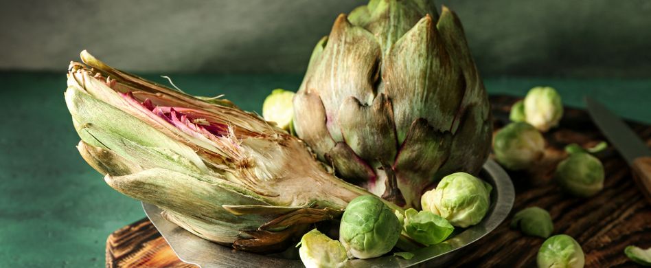artischocke mit rosenkohl auf holzbrett