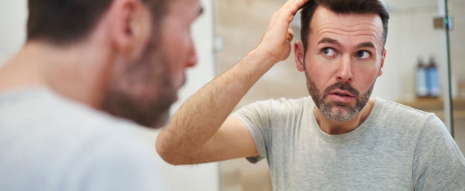 mann mit haarausfall vor spiegel