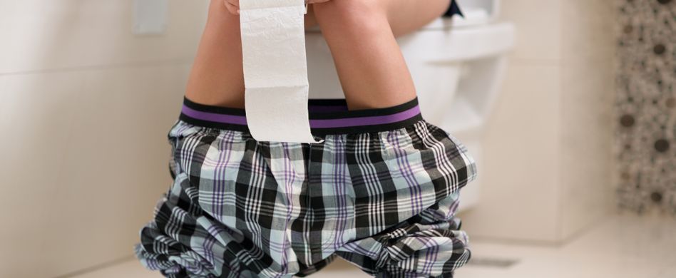 Person auf Toilette mit Klopapier