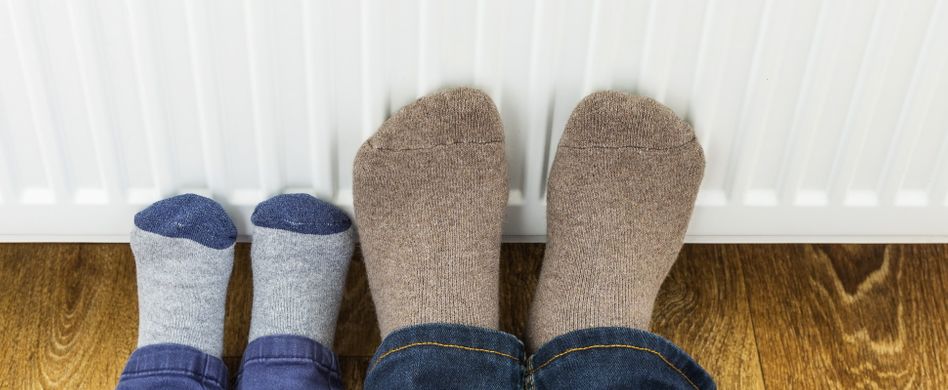 kind und erwachsener in socken wärmen ihre füße an der heizung