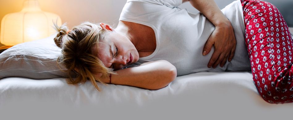 Frau mit Bauschmerzen liegt auf Sofa