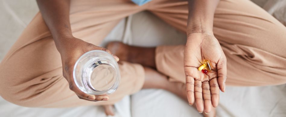 frau sitzt auf bett mit nahrungsergänzungsmittel in hand