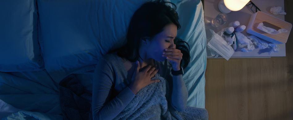 Frau krank im Bett hustet