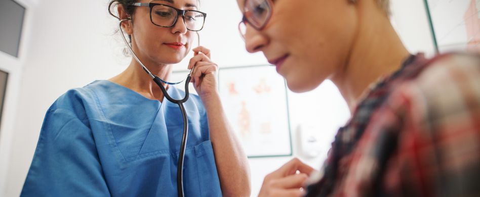 ärztin untersucht frau an brust mit stethoskop