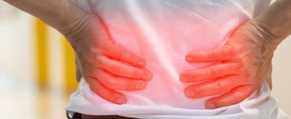 mann hält sich hände an den schmerzenden unterrücken