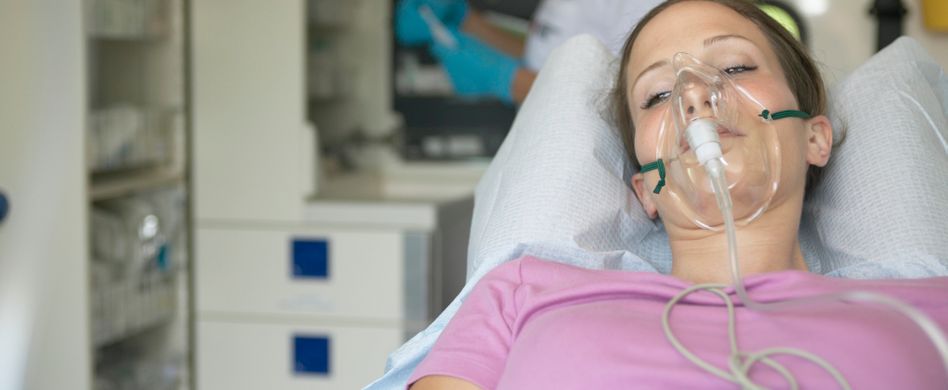 frau mit atemmaske auf einer liege im krankenhaus