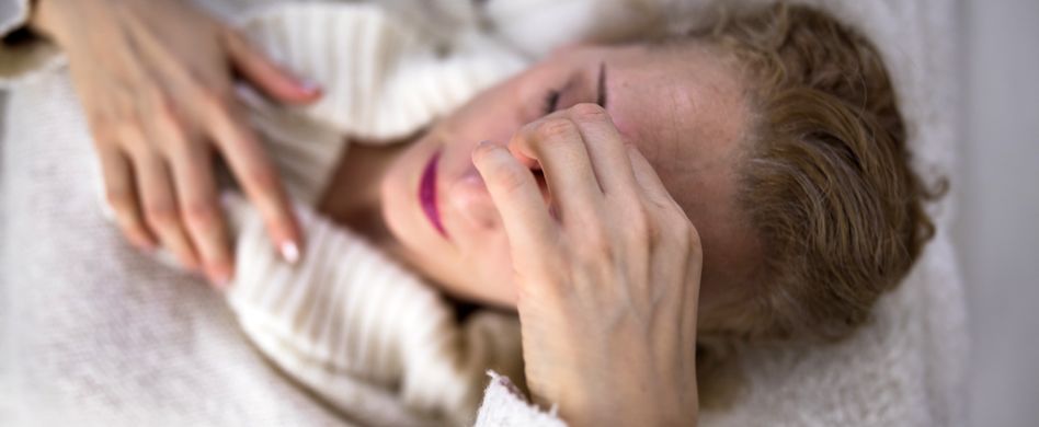 Frau mit Kopfschmerzen hält sich Stirn