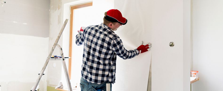 maler bringt weiße tapete an wand an