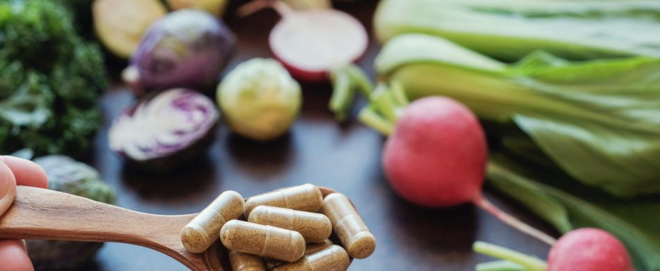 nahrungsergänzungsmittel auf löffel vor gemüse