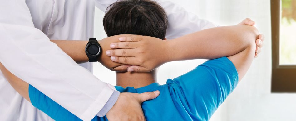 arzt behandelt rücken von mann mit blauem shirt