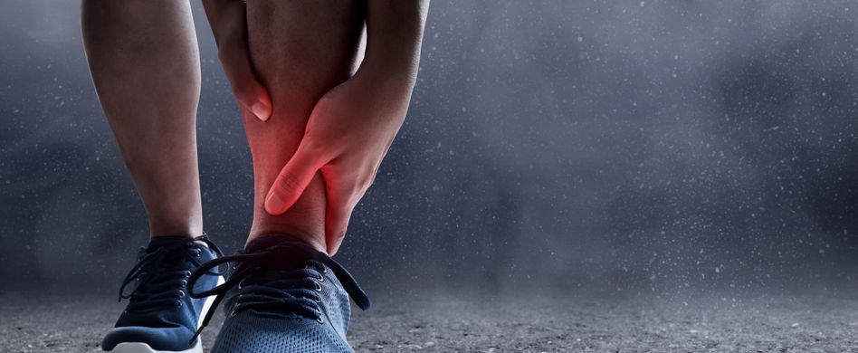 sportler hält sich den verletzten knöchel