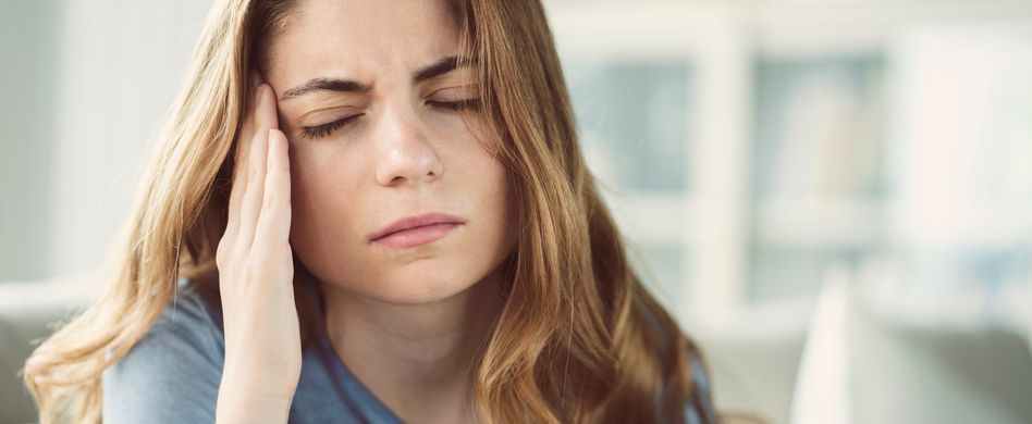 Frau hält sich Kopf vor Schmerz