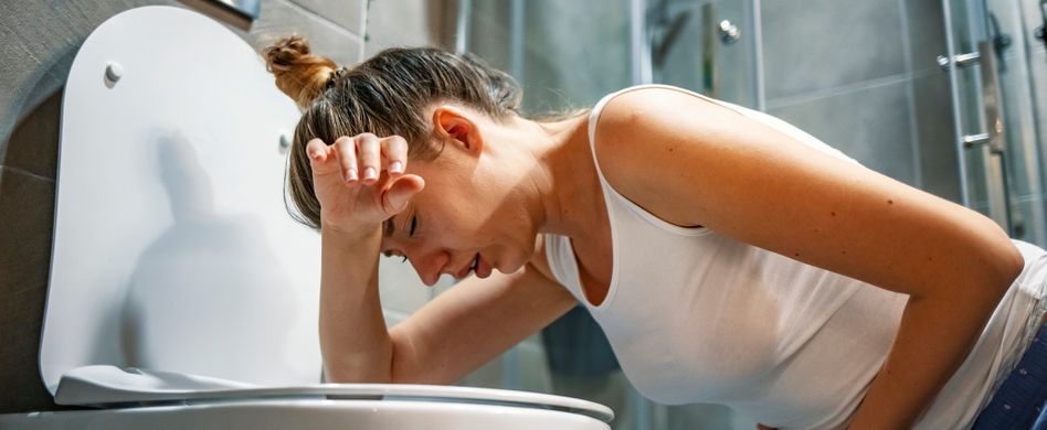 frau mit übelkeit kniet vor toilette