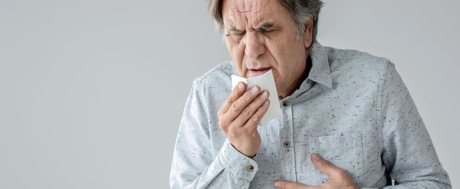 Mann hustet in Taschentuch mit Schmerzen in der Brust