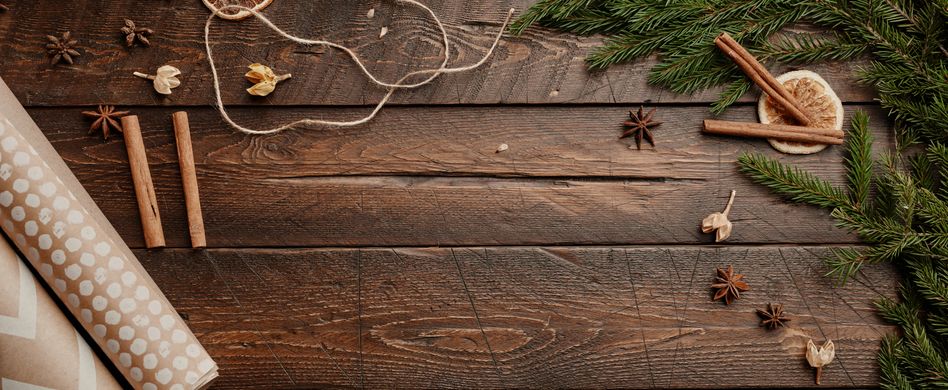 weihnachtsdeko zimt sternanis tannenzweige und geschenkpapier auf holzboden