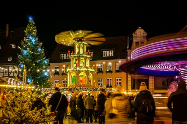 weihnachtsmarkt mit lichtern weihnachtsbaum karussell und besuchern bei nacht 