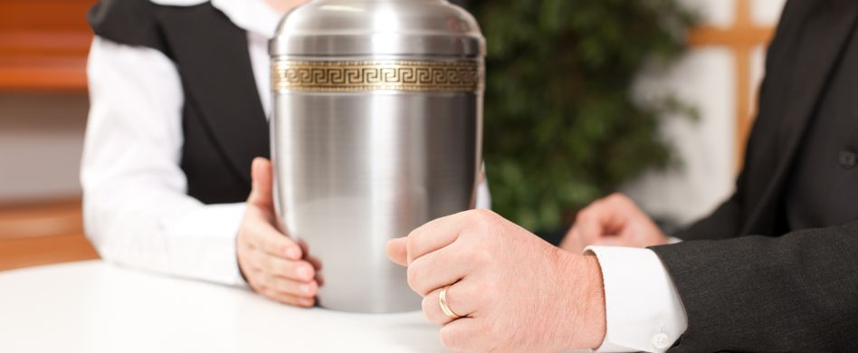 pfarrer und frau halten bei besprechung eine silberne urne